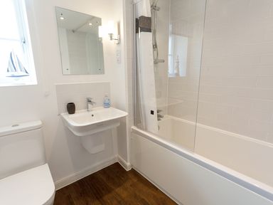 A bathroom with a toilet sink mirror bathtub and shower at Tus Nua Cottage in Carhampton