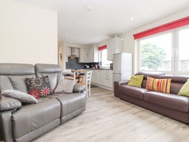 A living room with two sofas and pillows next to a kitchen with cabinets and a dining table at Jakanori in Staveley
