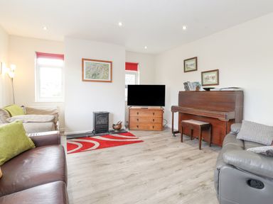 A living room with sofas a piano a television on a wooden cabinet and a red rug at Jakanori in Staveley