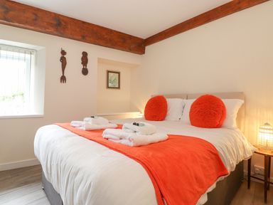 A bedroom with a bed featuring white bedding and orange accents at Jakanori in Staveley