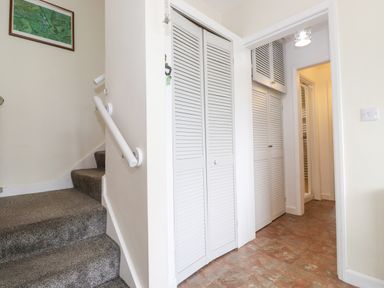 A hallway with carpeted stairs on the left white louvered closet doors on the right and a framed map on the wall at Jakanori in Staveley