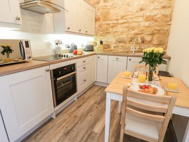 A kitchen with white cabinets wooden countertops a dining table set with breakfast at Lowdale Barns West Sleights