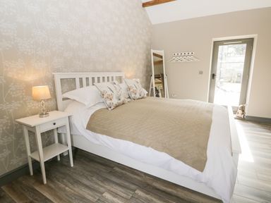 A bedroom with a bed side table with lamp and a bed with cushions and blanket at Lowdale Barns East in Sleights