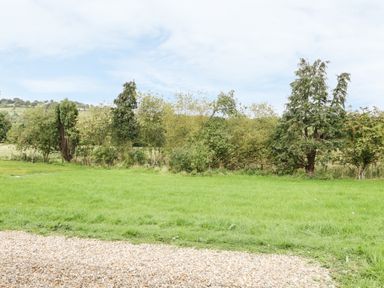 A grassy lawn with trees and hills in the background at Lowdale Barns East in Sleights