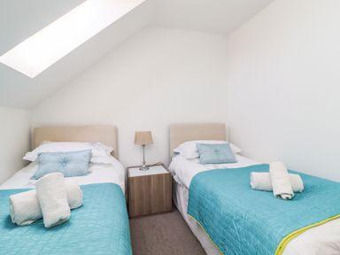A bedroom with two single beds blue bedspreads white pillows and towels on beds at 8 Pottergate Mews in Helmsley