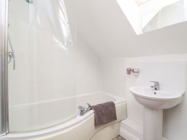 A bathroom with a bathtub shower combination and a pedestal sink at 8 Pottergate Mews in Helmsley