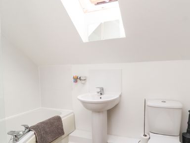 A bathroom with a bathtub a sink and a toilet under a skylight window at 8 Pottergate Mews in Helmsley