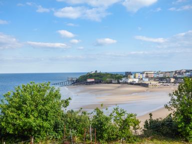 A coastal town with a sandy beach a pier and colorful buildings at Harbour Beach at The Hideaway in Tenby