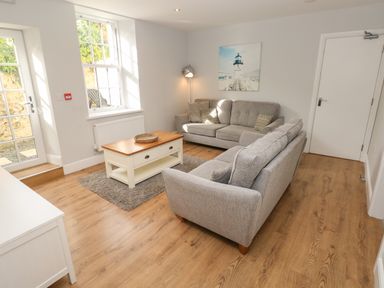 A living room with two gray sofas a wooden coffee table and a lamp at Harbour Beach at The Hideaway in Tenby
