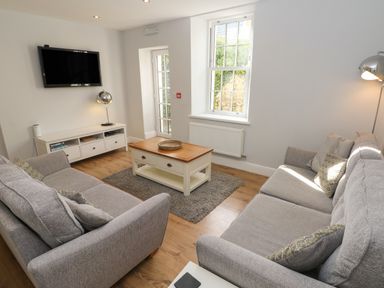A living room with two sofas a coffee table a rug and a wall-mounted television at Harbour Beach at The Hideaway in Tenby