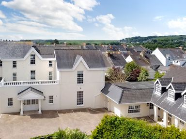 A view of houses with gray roofs and white walls with trees and hills in the background at Harbour Beach at The Hideaway in Tenby