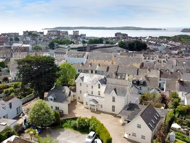 A view of a residential area with houses trees and a body of water in the background at Harbour Beach at The Hideaway in Tenby