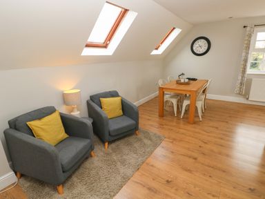 A living room with two armchairs and a wooden dining table at North Beach at The Hideaway in Tenby