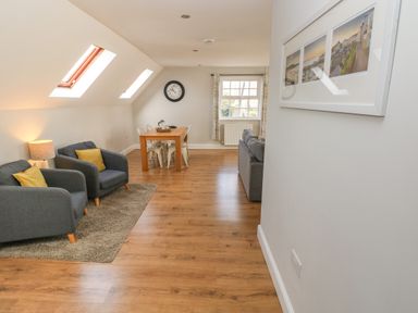 A living room with two armchairs a wooden dining table four chairs and a sofa at North Beach at The Hideaway in Tenby