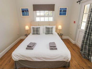 A bedroom with a double bed two bedside tables with lamps two framed pictures above the bed at North Beach at The Hideaway in Tenby