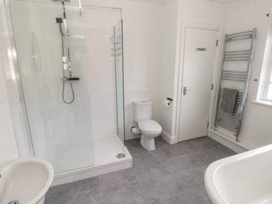 A bathroom with a glass shower enclosure a toilet a sink a heated towel rack and a door labeled private at North Beach at The Hideaway in Tenby