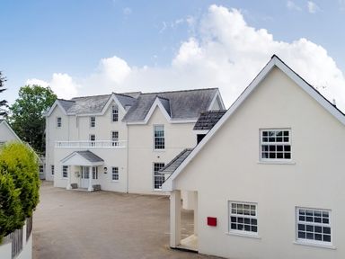 White two story residential buildings with multiple windows and a red mailbox under a blue sky at North Beach at The Hideaway in Tenby