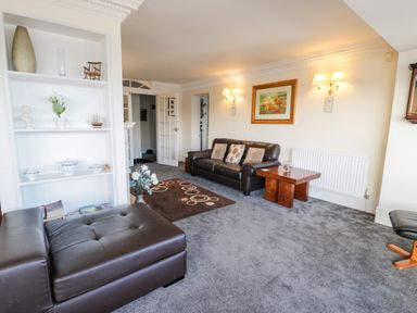 A living room with a leather sofa and ottoman a wooden coffee table built in shelving and a framed picture on the wall at 11 Glyn Garth Mews Llandegfan near Beaumaris