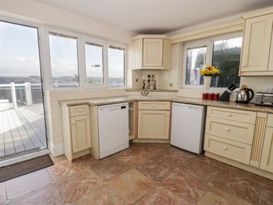 A kitchen with cream cabinets dishwasher and kettle by window at 11 Glyn Garth Mews Llandegfan near Beaumaris