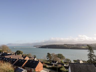 A view of a body of water with houses in the foreground and hills in the background at 11 Glyn Garth Mews in Llandegfan near Beaumaris