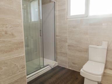 A bathroom with a shower enclosure and a toilet with a roll of toilet paper on top at 11 Glyn Garth Mews in Llandegfan near Beaumaris