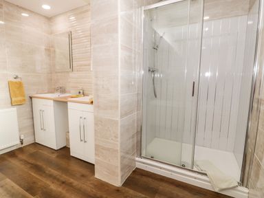 A bathroom with a double sink vanity and a glass enclosed shower at 11 Glyn Garth Mews in Llandegfan near Beaumaris