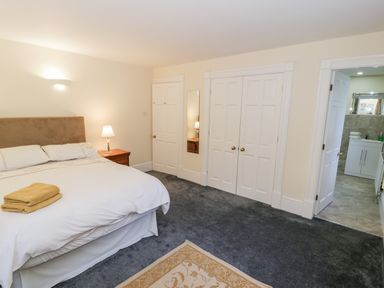 A bedroom with a bed side table lamp towels on bed white doors and an adjoining bathroom at 11 Glyn Garth Mews in Llandegfan near Beaumaris