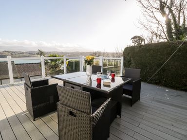 An outdoor patio with a table and four chairs with a vase of flowers and mugs at 11 Glyn Garth Mews in Llandegfan near Beaumaris