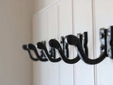 Black metal wall hooks attached to a white wooden panel