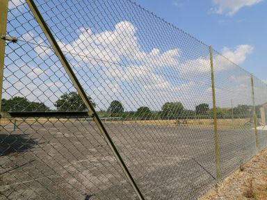 A chain link fence surrounding a paved area at The Apple Shed, Motcombe