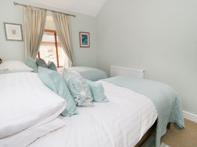 A bedroom with two beds a window with curtains and framed pictures on the walls at Llwyn Onn in Dolwyddelan