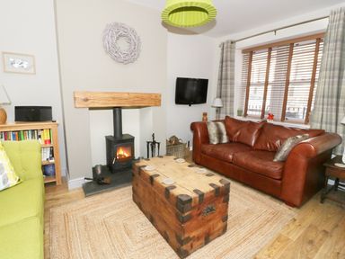 A living room with a green sofa a brown leather sofa wood burning stove and a wooden chest coffee table at Llwyn Onn in Dolwyddelan