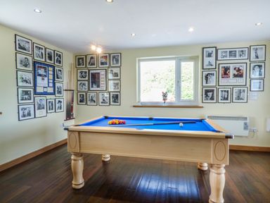 A room with a pool table with blue felt and framed pictures on the walls at Blue Oyster in Mullion near Lizard Point