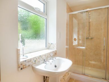 A bathroom with a pedestal sink and a glass enclosed shower at Blue Oyster in Mullion near Lizard Point