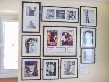 A wall with multiple framed black and white and color photos including movie scenes and portraits at Blue Oyster in Mullion near Lizard Point