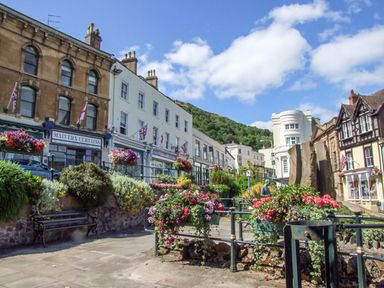 A street scene with buildings shops flower planters and a hill in the background at The Packing House in Hanley Castle near Malvern