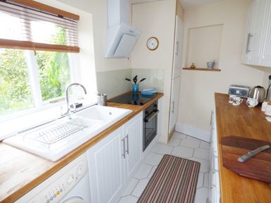A kitchen with a sink and stove and wooden countertops and white cabinets at The Packing House in Hanley Castle near Malvern