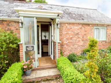 A brick house entrance with a glass porch door and plants outside at The Packing House in Hanley Castle near Malvern