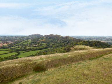 A landscape view of rolling hills and green fields with scattered trees at The Packing House in Hanley Castle near Malvern