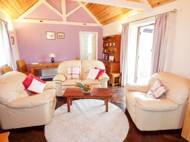 A living room with beige sofas pillows a wooden coffee table and a circular rug at The Packing House in Hanley Castle near Malvern