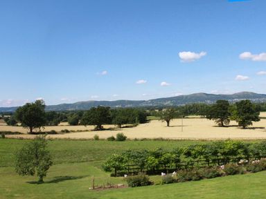 A rural landscape with fields trees and hills under a blue sky at The Packing House in Hanley Castle near Malvern