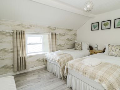 A bedroom with two single beds bedside table window and framed pictures on the wall at Marsh Villa in Silloth