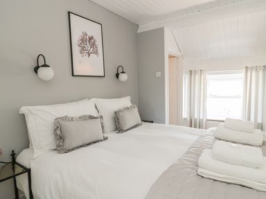 A bedroom with a white bed and pillows with bedside tables and wall lamps at Marsh Villa in Silloth
