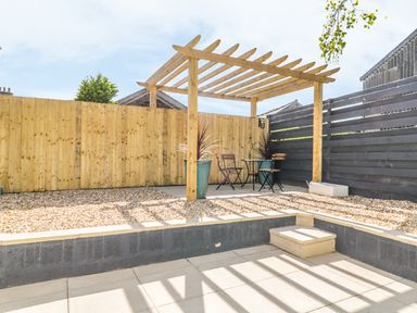 A small outdoor seating area with pergola wooden fences and gravel ground at Marsh Villa in Silloth