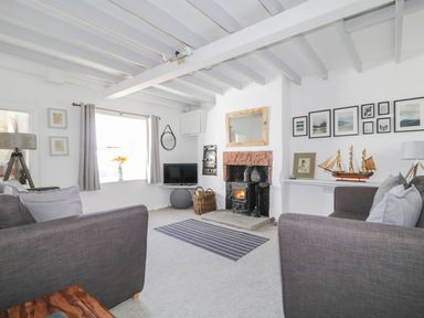 A living room with two grey sofas a fireplace a TV and a model ship at Marsh Villa in Silloth