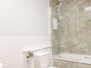 A bathroom with a toilet and a bathtub with shower at Victoria Cottage in Norham
