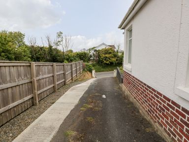 A driveway beside a house with a wooden fence and greenery in the background at White Thorns in Haverfordwest