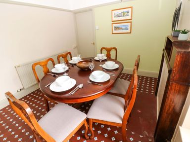 A dining room with a table set for dinner at White Thorns in Haverfordwest