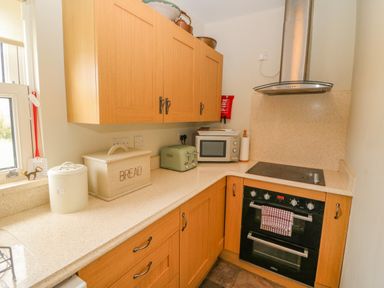 A kitchen corner with wooden cabinets a microwave toaster bread box and stove with oven at Shandrum Brook Charleville