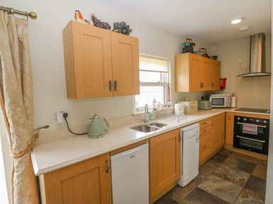 A kitchen with wooden cabinets a sink countertop appliances and curtains at Shandrum Brook in Charleville